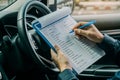 Machinic man in customer car writing to the clipboard the checklist for repair machine, car service and maintenance.Services car