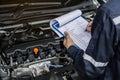 machinic man writing to the clipboard the checklist for repair machine, car service and maintenance.Services car engine machine