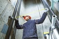 Machinist with measure tape checking lift construction in elevator shaft