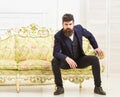 Macho attractive and elegant on serious, thoughtful face sitting on old fashioned luxury sofa. Fashion and style concept