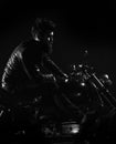 Macho, brutal biker in leather jacket riding motorcycle at night time, copy space. Man with beard, biker in leather