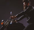 Macho, brutal biker in leather jacket riding motorcycle at night time, copy space. Masculinity concept. Man with beard Royalty Free Stock Photo