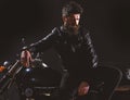 Macho, brutal biker in leather jacket stand near motorcycle at night time. Brutality and masculine concept. Man with