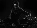 Macho, brutal biker in leather jacket stand near motorcycle at night time. Brutality and masculine concept. Man with