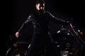 Macho, brutal biker in leather jacket stand near motorcycle at night time, copy space. Man with beard, biker in leather