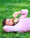 Macho with daisies in beard relaxing. Bearded man with daisy flowers in beard lay on grassplot, grass background. Man