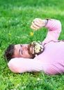 Macho with daisies in beard relaxing. Bearded man with daisy flowers in beard lay on grassplot, grass background