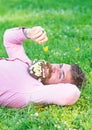 Macho with daisies in beard relaxing. Bearded man with daisy flowers in beard lay on grassplot, grass background