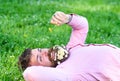 Macho with daisies in beard relaxing. Bearded man with daisy flowers in beard lay on grassplot, grass background. Peace Royalty Free Stock Photo