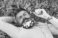 Macho with daisies in beard relaxing. Bearded man with daisy flowers in beard lay on grassplot, grass background. Pollen Royalty Free Stock Photo