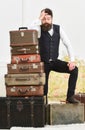 Macho elegant on disappointed face standing near pile of vintage suitcase. Luggage and travelling concept. Man, butler Royalty Free Stock Photo