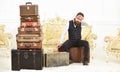 Macho elegant on strict face sits tired near pile of vintage suitcase. Man, butler with beard and mustache delivers