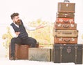 Macho elegant on surprised face sits shocked near pile of vintage suitcase. Luggage and travelling concept. Man, butler Royalty Free Stock Photo