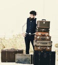 Macho elegant on tired face, exhausted at end of packing, leans on pile of vintage suitcases. Man with beard and