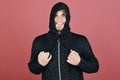 Macho with happy smiling face ties hood tightly. Guy with bristle in dark grey and black hoodie