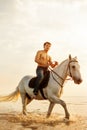 Macho man and horse on the background of sky and water. Boy mode Royalty Free Stock Photo