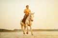 Macho man and horse on the background of sky and water. Boy mode Royalty Free Stock Photo