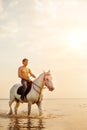 Macho man and horse on the background of sky and water. Boy mode Royalty Free Stock Photo