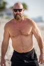 Macho tough guy walking on the beach. Man is wearing sunglasses and no shirt Royalty Free Stock Photo