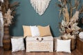 Macrame decoration with brown flower, box, pillows and cane before green wall