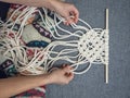 Macrame. Girl weaves macrame. White thread, female hand, grey background, close-up