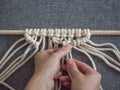 Macrame. Girl weaves macrame. White thread, female hand, grey background, close-up Royalty Free Stock Photo