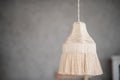 Macrame lamp hangs on gray plain background. Handmade hobby. Decoration in Boho style. Scandinavian