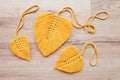 Macrame leaves in yellow color on the wooden background. Cotton rope decor macrame to make your home more cozy and unique. Woman