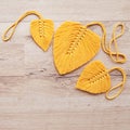 Macrame leaves in yellow color on the wooden background. Cotton rope decor macrame to make your home more cozy and unique. Woman