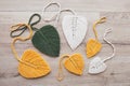 Macrame leaves in yellow, green and natural color on the wooden background. Cotton rope decor macrame to make your home more cozy