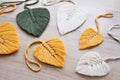 Macrame leaves in yellow, green and natural color on the wooden background. Cotton rope decor macrame to make your home more cozy