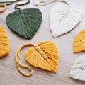 Macrame leaves in yellow, green and natural color on the wooden background. Cotton rope decor macrame to make your home more cozy