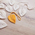 Macrame leaves in yellow and natural color on the wooden background. Cotton rope decor macrame to make your home more cozy and