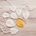 Macrame leaves in yellow and natural color on the wooden background. Cotton rope decor macrame to make your home more cozy and