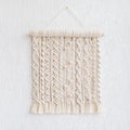 Macrame wallhanging with wooden beads. Wall panel of cotton threads in natural color. Macrame technique for eco home decor. Modern Royalty Free Stock Photo
