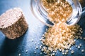 Macro Of Brown Raw Sugar Spilled Out Of An Overturned Glass Bottle Next To A Cork Stopper On Slate Stone Royalty Free Stock Photo