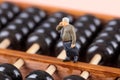Macro business man doll standing on Chinese abacus making a call