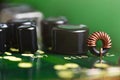 Macro of circuit board with electronic components and toroidal coil wrapped with copper wire on green background