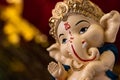 Macro close up of beautiful ganesha statue in blessing pose against blurred red and golden background. religion and hindu concept