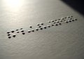 Braille Text Embossed on Textured Surface with Shadowed Dots in Macro Close-Up Royalty Free Stock Photo