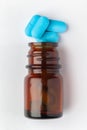 Macro Close up of medicinal or herbal cyan tablet spilled and in an amber glass bottle. Top view,