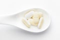 Macro Close up of medicinal or herbal light yellow tablet on a white ceramic spoon. white background.