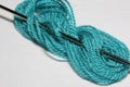 Macro close-up of needle is threaded into the thread of blue yarn