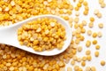 Macro Close-up of Organic Bengal Gram Cicer arietinum or split yellow chana dal on a white ceramic soup spoon. Top view, over