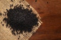 Macro close-up of Organic black cumin Nigella sativa or kalonji on the wooden top background and jute mat.