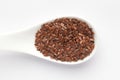 Macro Close up of Organic Brown flaxseeds Linum usitatissimum or linseed on a white ceramic soup spoon.