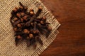 Macro close-up of Organic Clove Syzygium aromaticum or Indian long on wooden top background and jute mat. Royalty Free Stock Photo