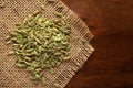 Macro close-up of Organic Fennel Seeds Foeniculum vulgare Badi sonf on the wooden top background and jute mat.