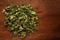 Macro close-up of Organic green dry Fenugreek leaves Trigonella foenum-graecum on wooden top background. Pile of Indian Aromatic