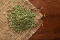 Macro close-up of Organic green fennel seed Foeniculum vulgare small size on wooden top background and jute mat.